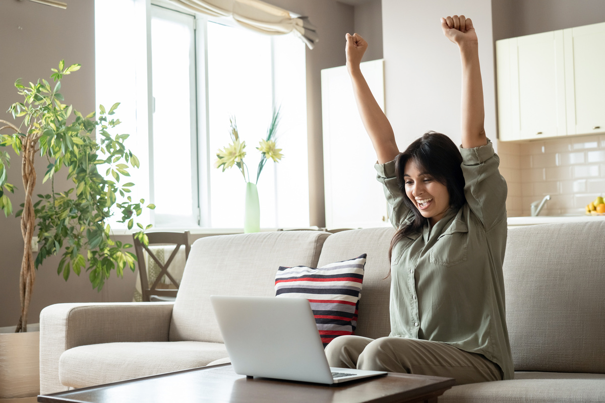 Woman Celebrating Online Win Looking at Laptop at Home